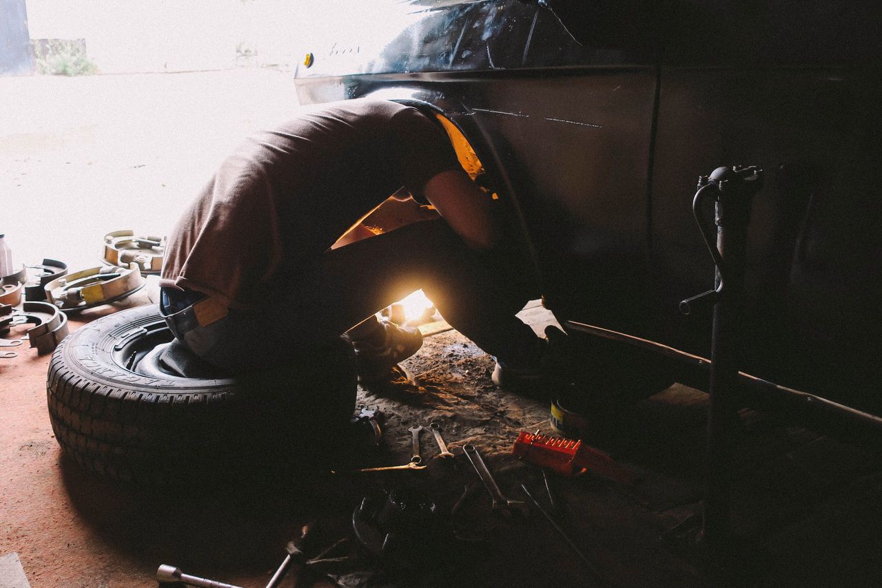 A dedicated mechanic intensely focused on repairing a car wheel in an auto repair shop.